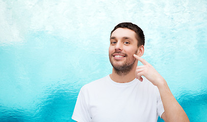 Image showing smiling young handsome man pointing to cheek