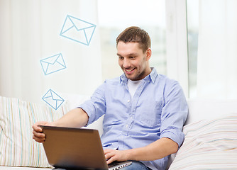 Image showing smiling man working with laptop at home