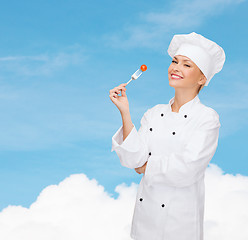 Image showing smiling female chef with fork and tomato