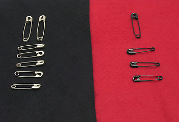 Image showing Several fixing pins on black and red felt