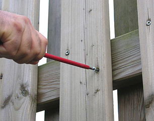 Image showing Cutout hand with screw driver on wooden fence