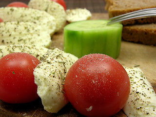 Image showing Sliced mozzarella with little tomatoes, a slice of cucumber and wholemeal bread