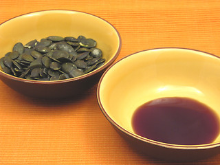 Image showing Two bowls of ceramic with pumpkin seeds and pumpkin seed oil