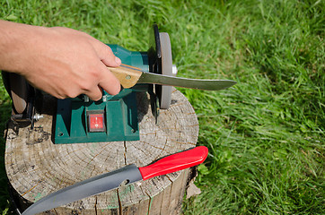 Image showing Hand grinder knife with electric tool outdoor log 