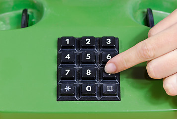 Image showing fingers press dial buttons on old retro telephone 