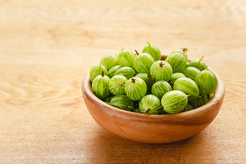 Image showing Close-Up Of Gooseberries In Vintage Wooden Bowl On Wooden Table