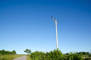 Image showing Pole with powerlines at blue sky