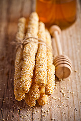 Image showing bread sticks grissini with sesame seeds and honey