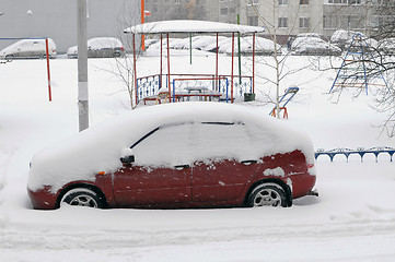Image showing The red car, brought by snow is in the house yard.