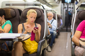 Image showing Lady traveling by train using smartphone.