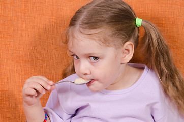 Image showing Girl eats honey spoon