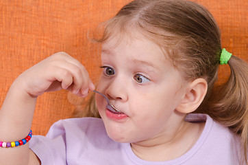 Image showing Funny girl squinted with his spoon in mouth