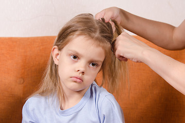 Image showing Mom braids hair sad girl