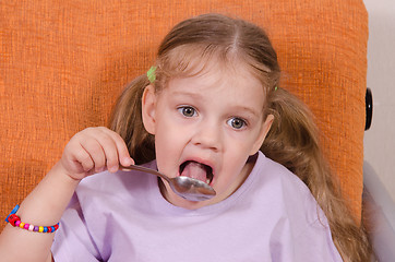 Image showing Girl licks a spoon with honey