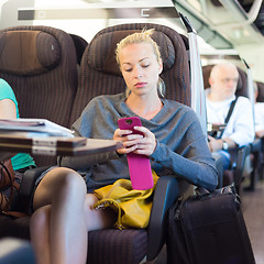 Image showing Lady traveling by train using smartphone.