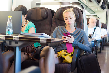 Image showing Lady traveling by train using smartphone.