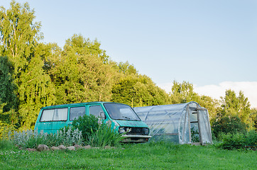 Image showing mini bus parked next to village greenhouse in yard 