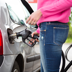 Image showing Lady pumping gasoline fuel in car at gas station.