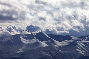 Image showing Evening sunlight mountain with clouds and silhouette of paraglid