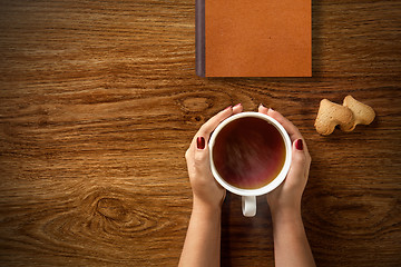 Image showing woman with cup of tea, cookies and book on wood