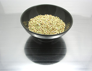 Image showing Black bowl of chinaware with buckwheat on reflecting surface