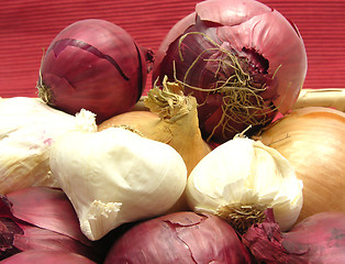 Image showing Onions and garlics in a basket in front of red background