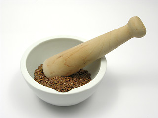 Image showing Pestling brown flaxseed in a bowl of chinaware