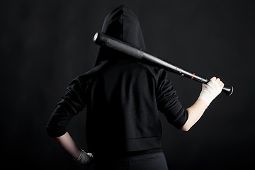 Image showing Young woman with a baseball bat. View from the back. hoodlum