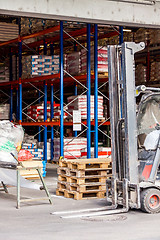 Image showing Small orange forklift parked at a warehouse