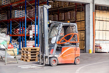 Image showing Small orange forklift parked at a warehouse