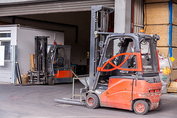 Image showing Small orange forklift parked at a warehouse