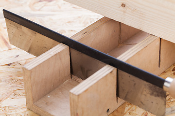 Image showing Hand saw cutting through a beam of wood