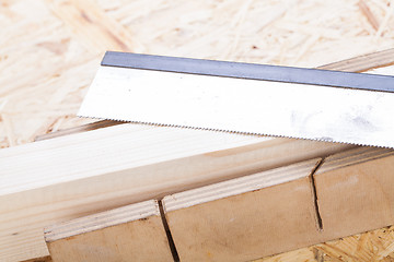 Image showing Hand saw cutting through a beam of wood