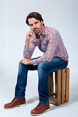 Image showing Handsome young man sitting on a wooden box