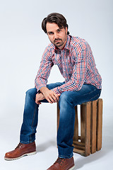 Image showing Handsome young man sitting on a wooden box