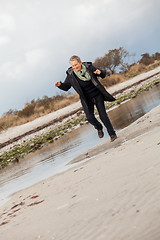 Image showing Happy senior woman frolicking on the beach