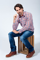 Image showing Handsome young man sitting on a wooden box