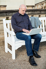 Image showing Man sitting on a bench using a laptop