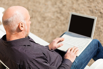 Image showing Man sitting on a bench using a laptop