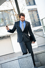 Image showing Smiling businessman walking down stairs