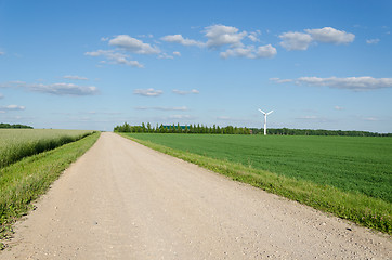 Image showing Rural gravel road near fields and windmill 