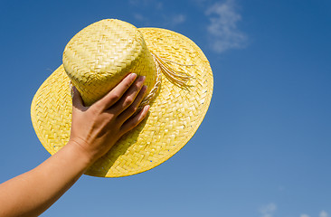 Image showing hand hold yellow straw hut on blue sky background 