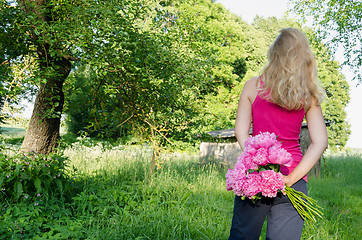 Image showing woman back view peony in hand garden background