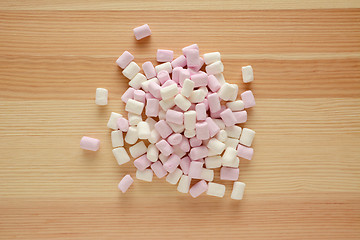 Image showing Pink and white mini marshmallows on wood