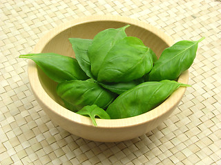Image showing Wooden bowl with basil on rattan underlay