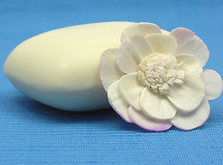 Image showing Beige soap with decoration articles on a  light blue background