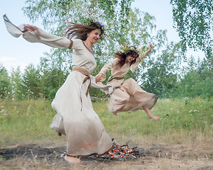 Image showing Attractive girls jump through fire