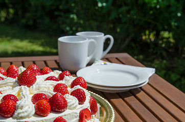 Image showing Table with strawberry cake and coffee cups in background