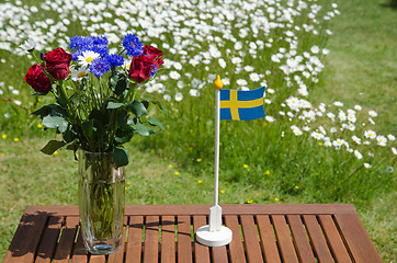 Image showing Table with summer flowers and a swedish flag