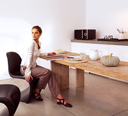 Image showing Young beautiful woman sitting in kitchen